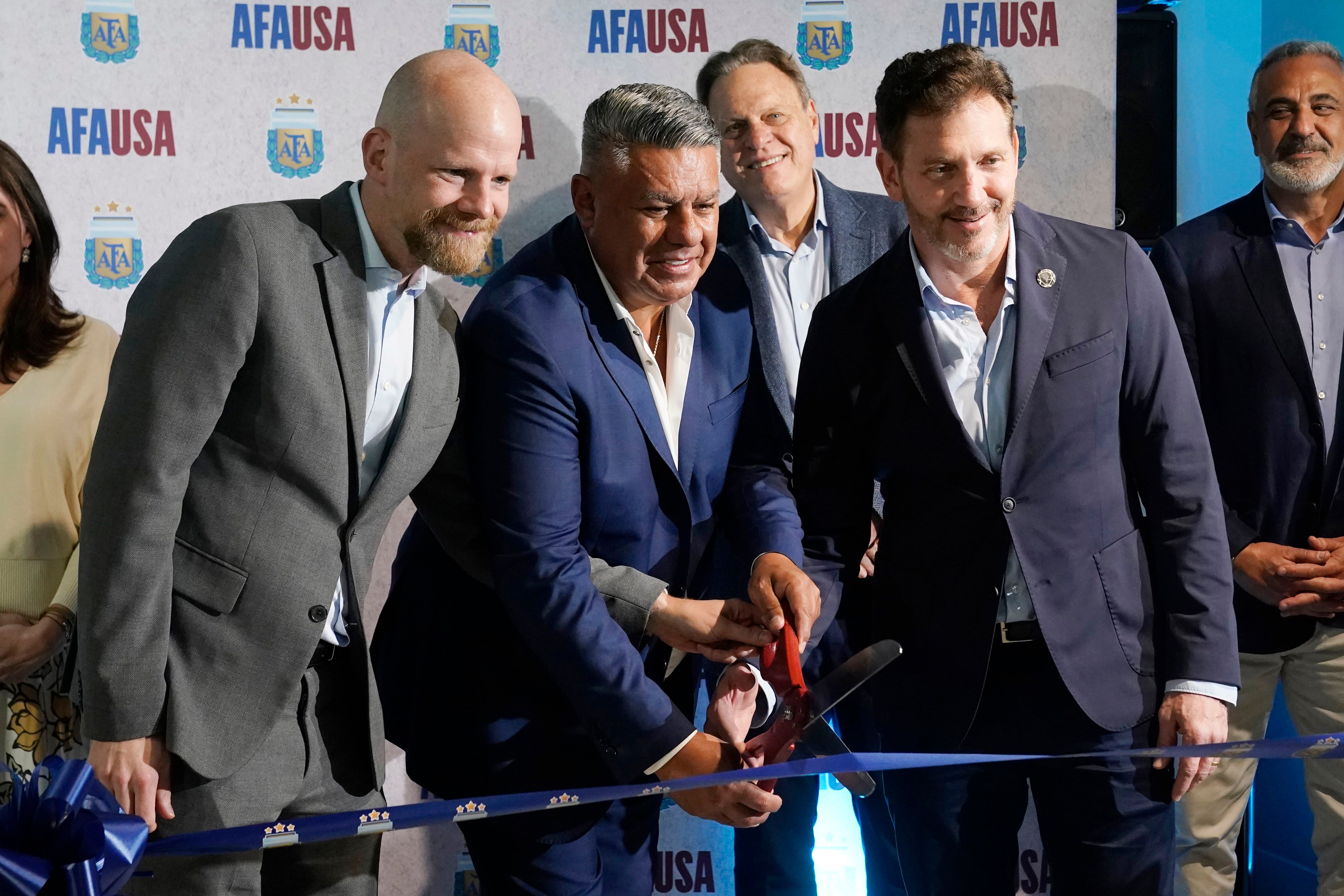 El presidente de la Asociación del Fútbol Argentino, Claudio "Chiqui" Tapia (centro); el secretario general de la FIFA Mattias Grafstrom (izquierda); y el presidente de la CONMEBOL Alejandro Domínguez (derecha) en la inauguración de la sede de la AFA en Miami, el jueves 7 de diciembre de 2023 (AP Foto/Marta Lavandier)