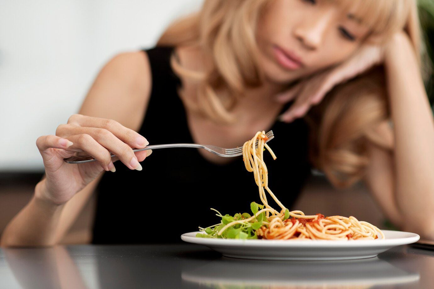 Mujer sin ganas de comer un plato de fideos (Freepik)