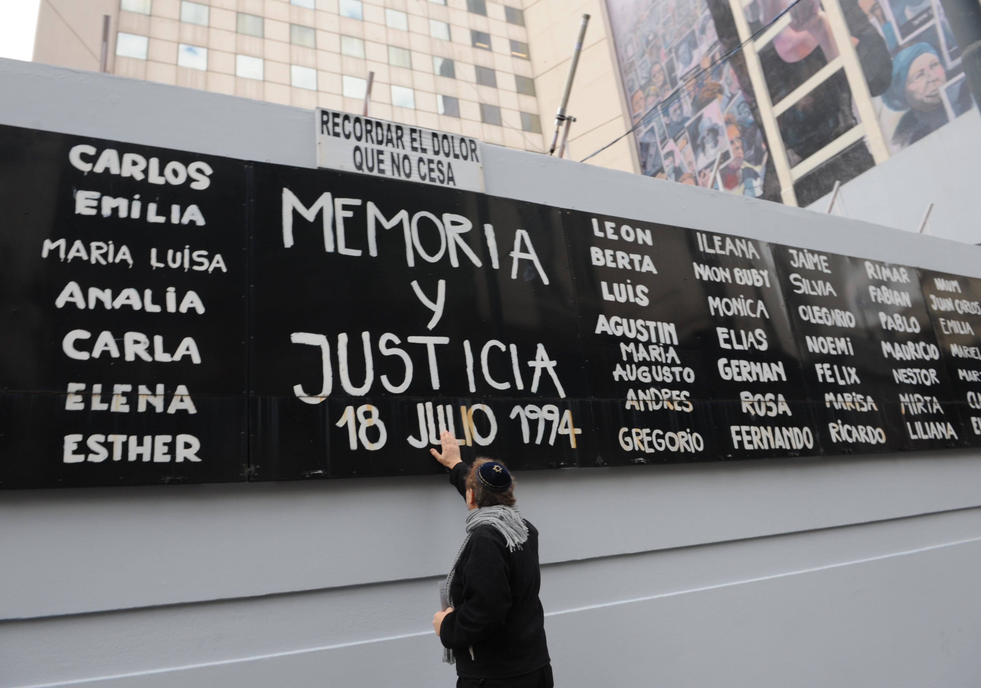 Fotografía de archivo de un hombre tocando un cartel con nombres de víctimas durante un acto conmemorativo por los 25 años del atentado contra la mutua judía AMIA, en Buenos Aires (Argentina). EFE/ Enrique G. Medina 