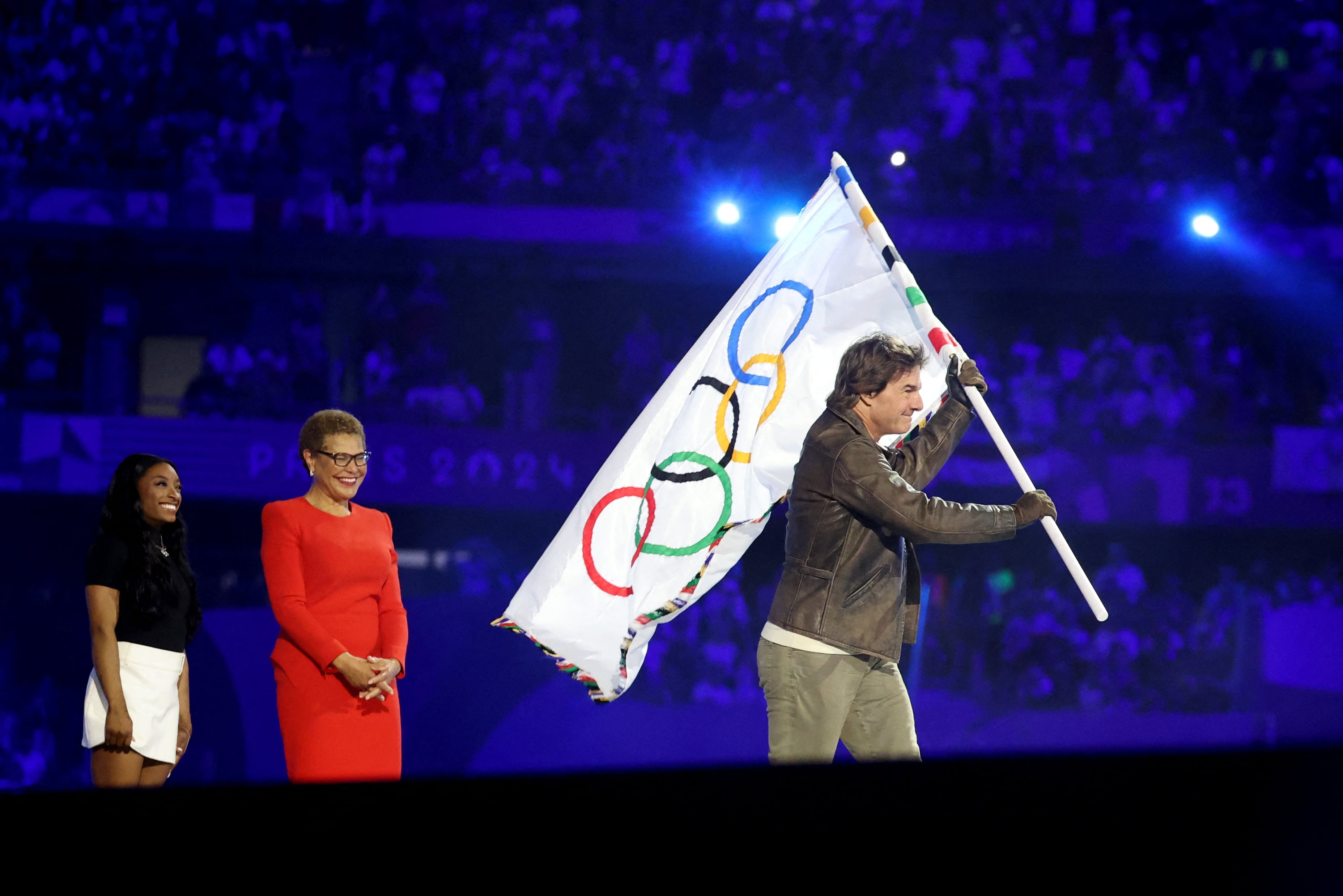 Karen Bass, alcaldesa de Los Ángeles, y Simone Biles, ya le entregaron a Tom Cruise la bandera olímpica durante la ceremonia (REUTERS/Fabrizio Bensch/Pool)