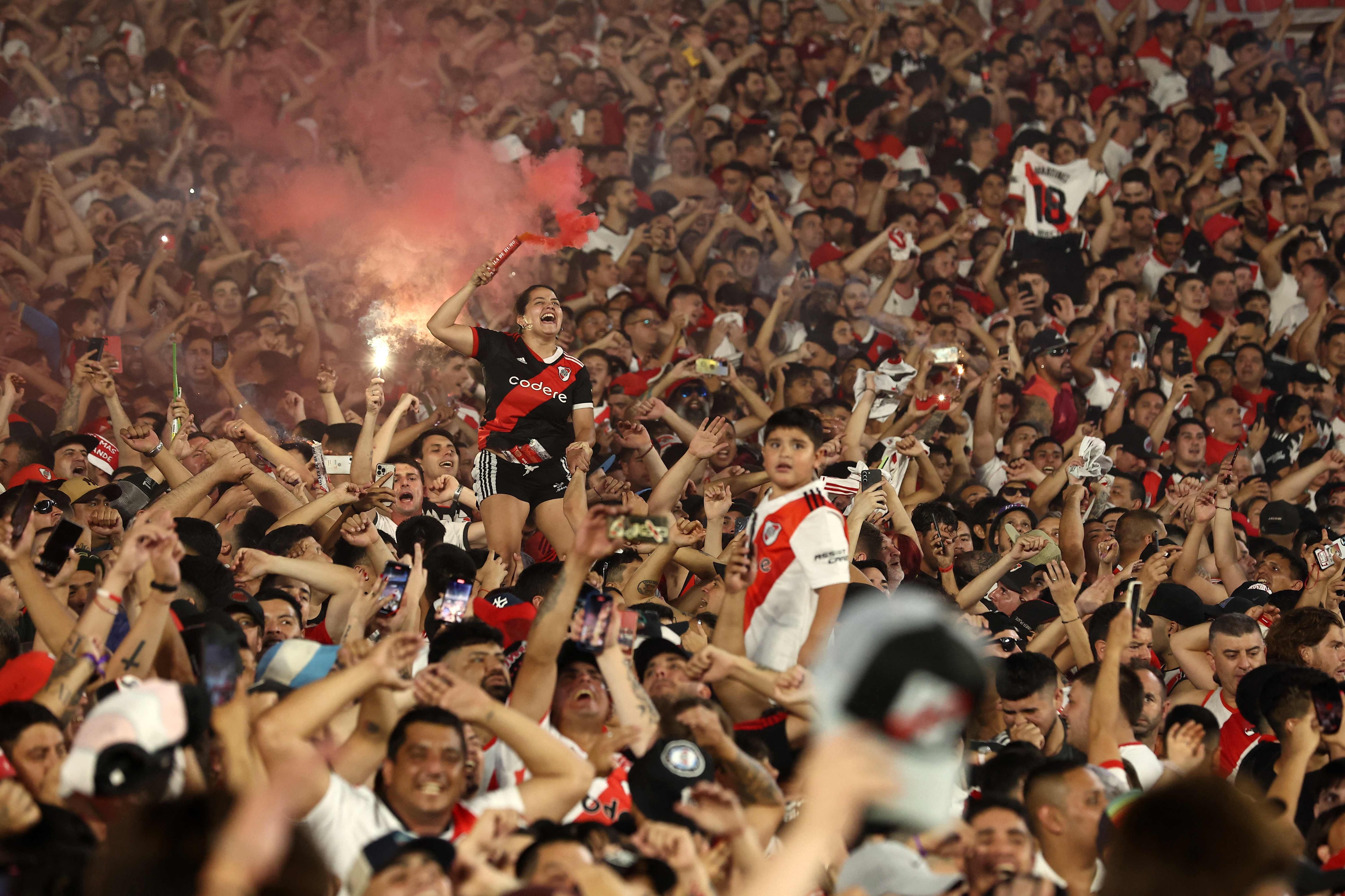 TOPSHOT - A River Plate fan holds a red smoke flare before the Copa Libertadores semi-final second leg football match between Argentina's River Plate and Brazil's Atletico Mineiro at the Mas Monumental stadium in Buenos Aires on October 29, 2024. (Photo by ALEJANDRO PAGNI / AFP)