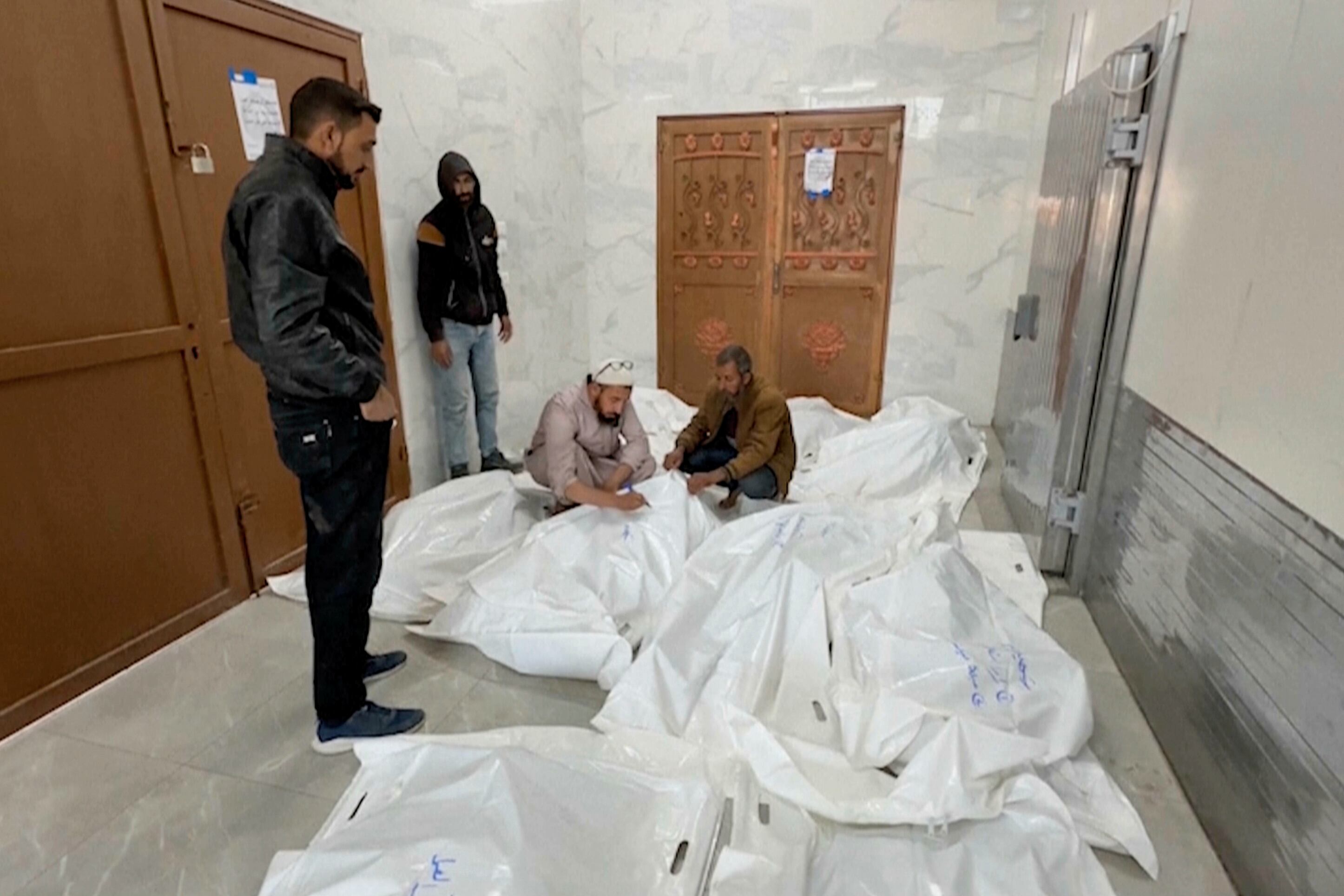 Palestinos en una morgue con los cadáveres de parientes fallecidos en los ataques aéreos en la ciudad de Jan Yunis, en el sur de la Franja de Gaza (AP Foto)