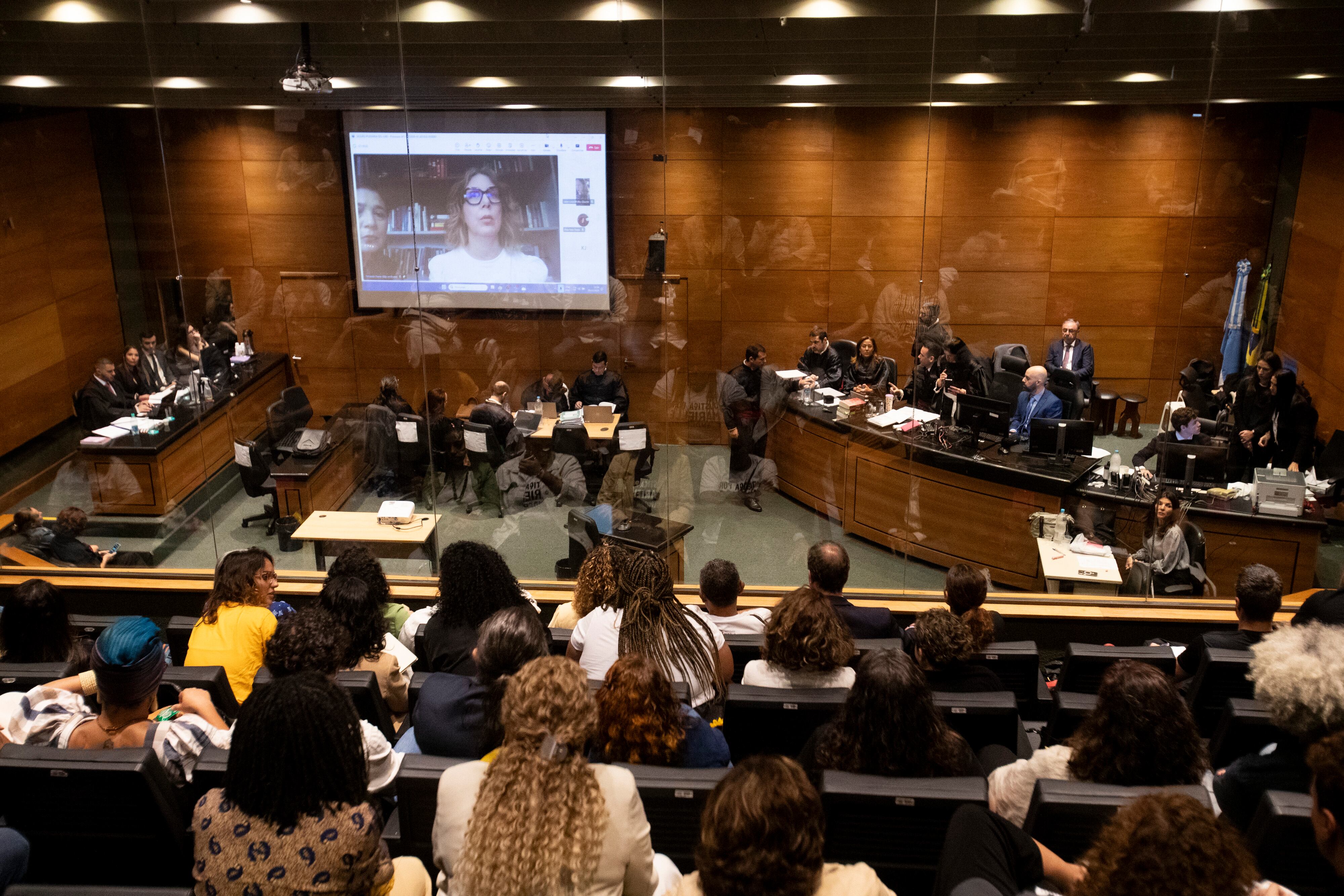 Fernanda Goncalves Chaves, asistente de la concejala brasileña asesinada Marielle Franco, en la pantalla, testifica en el juicio a los acusados de matar a Franco, en un tribunal de Rio de Janeiro, el 30 de octubre del 2024. (AP Foto/Bruna Prado)