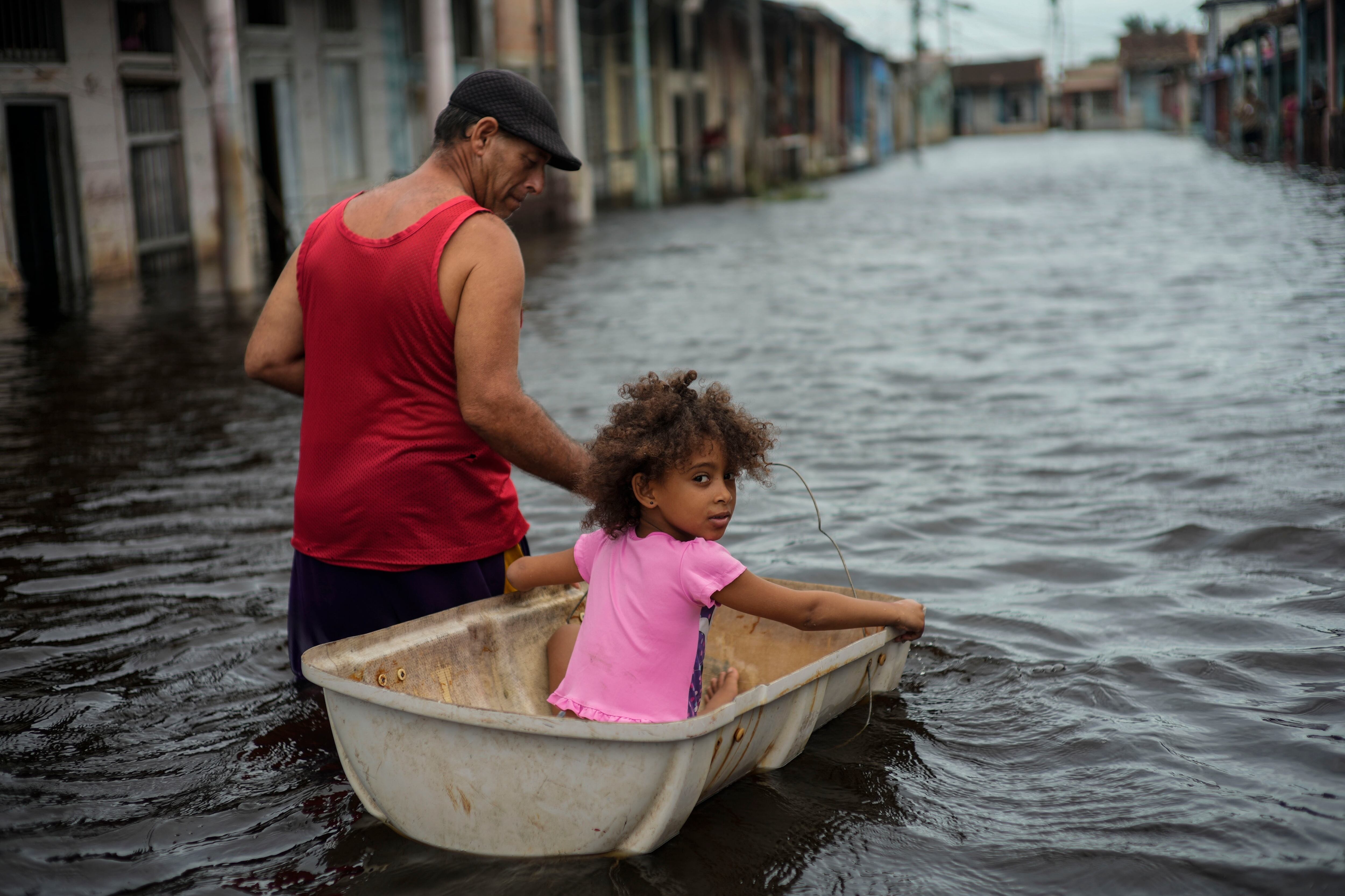 Jesús Hernández con su nieta Angelina en una calle inundada tras el paso del huracán Helene en Batabano, provincia de Mayabeque, Cuba, el 26 de septiembre del 2024. (Foto AP /Ramon Espinosa)